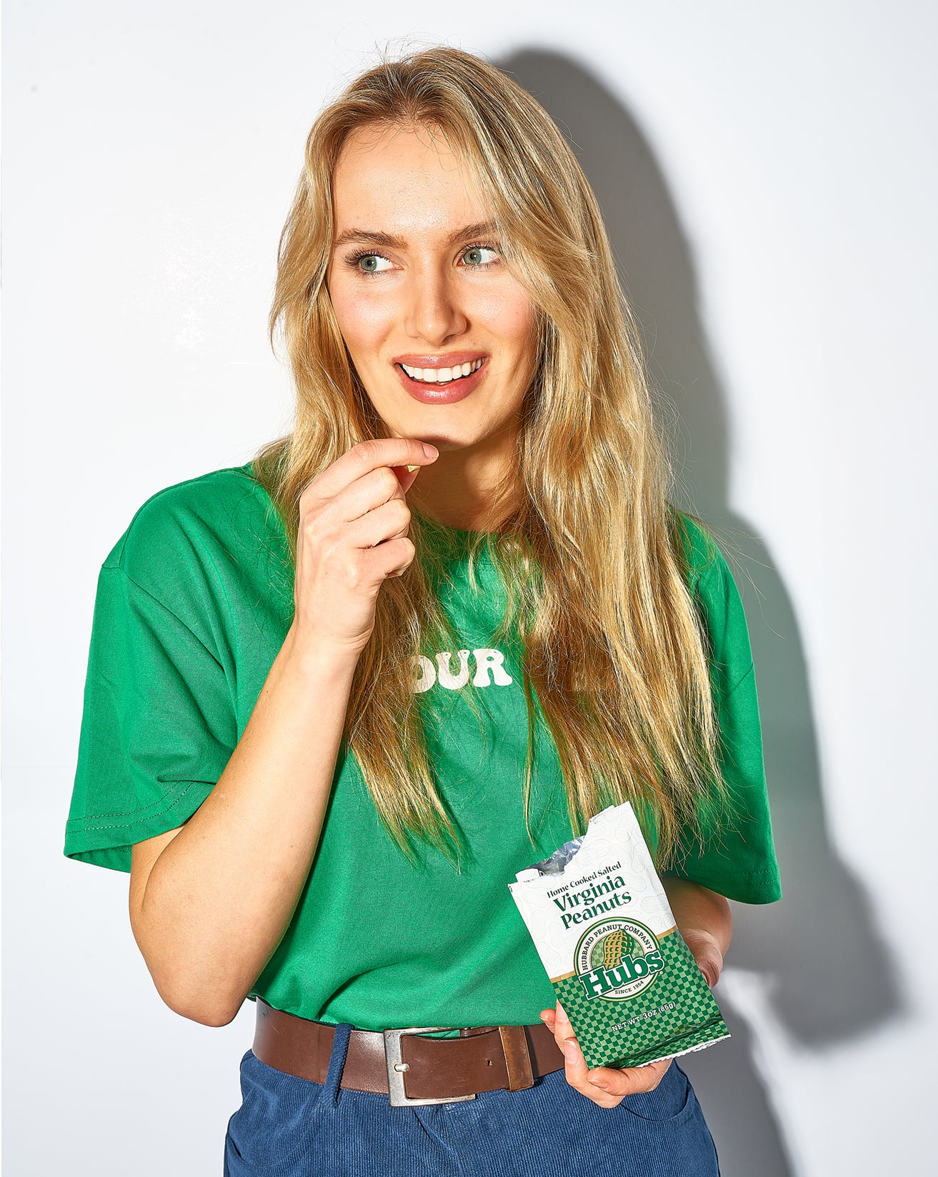 woman eating Hubs power pack Peanuts in a green shirt